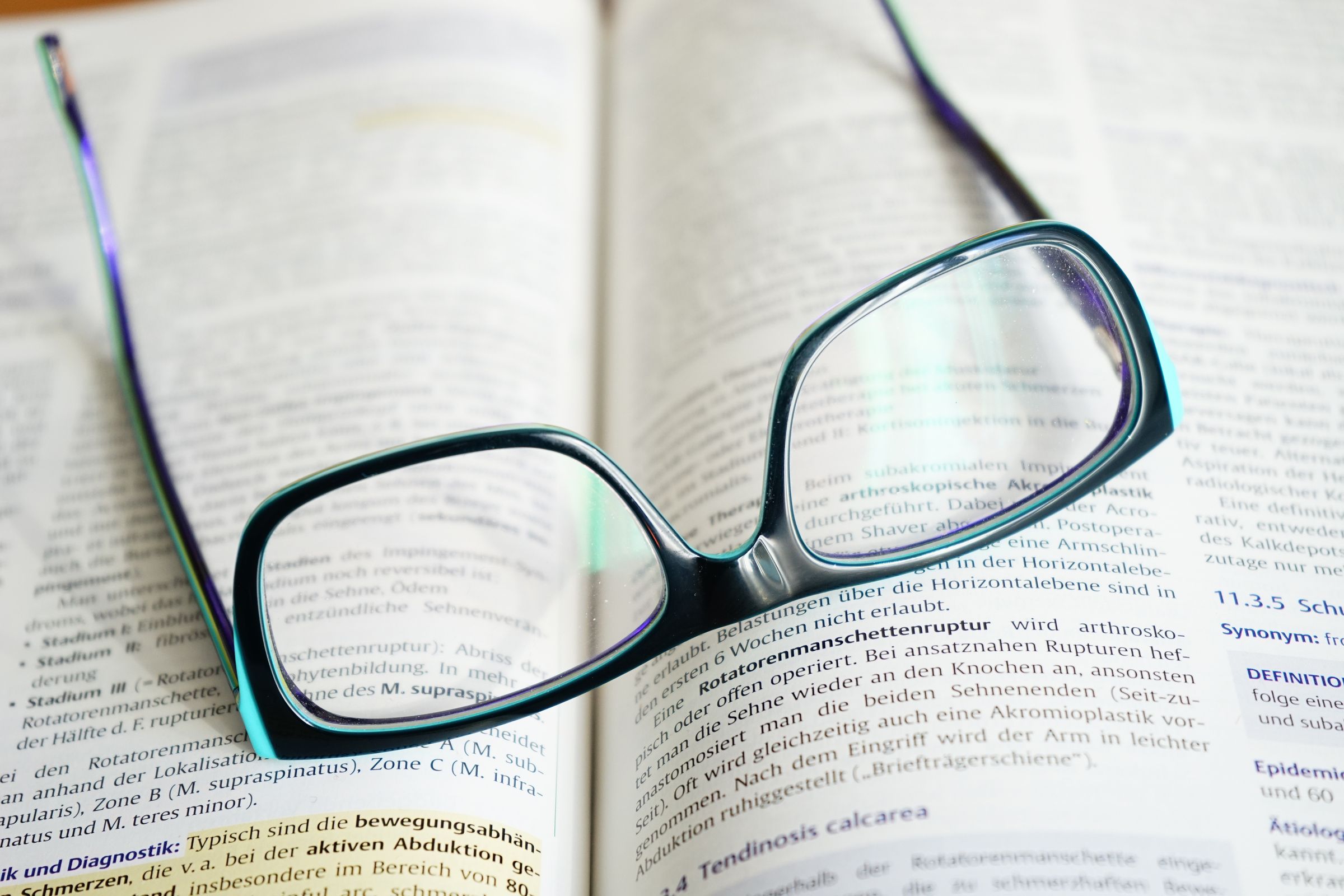 A pair of reading glasses resting on an open textbook